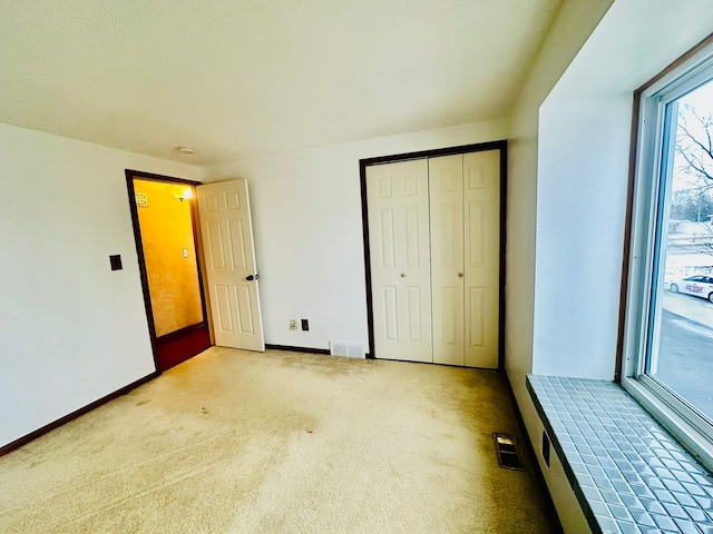 unfurnished bedroom featuring light colored carpet, a closet, and access to outside