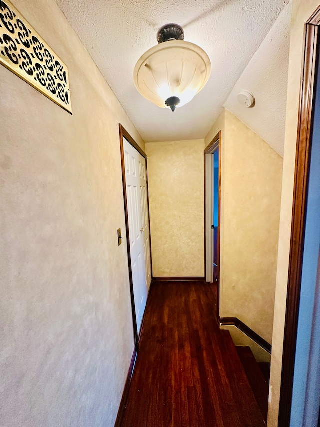 hallway featuring dark wood-type flooring and a textured ceiling