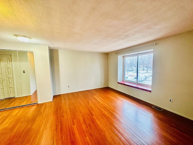 empty room featuring wood-type flooring and a textured ceiling