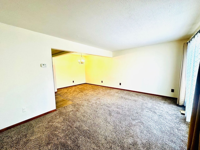 carpeted empty room featuring a textured ceiling and a notable chandelier