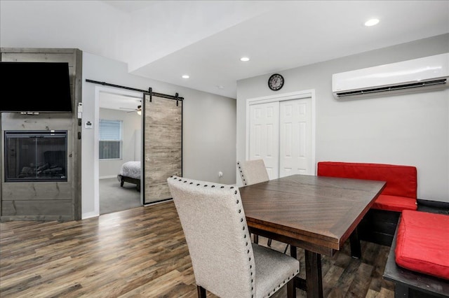 dining space featuring a wall mounted air conditioner, dark hardwood / wood-style floors, and a barn door