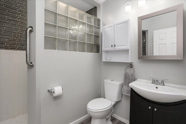 bathroom with vanity, toilet, and a tile shower