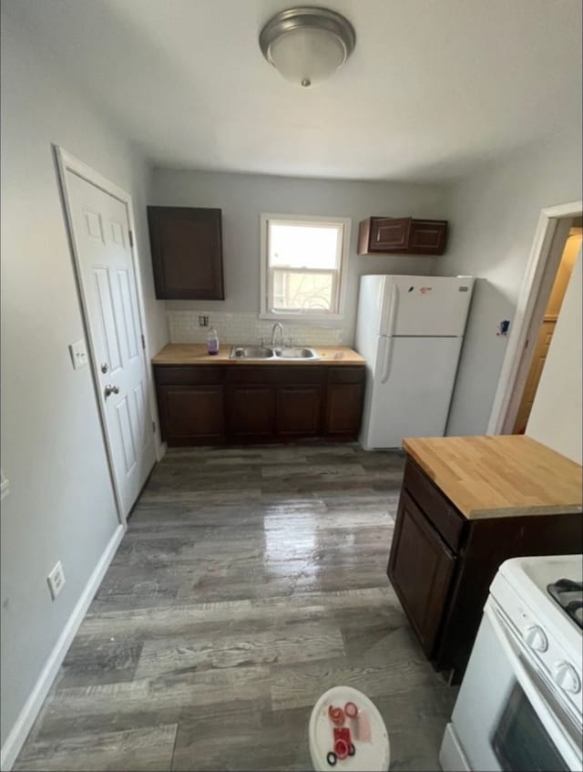 kitchen with white appliances, wood-type flooring, wooden counters, sink, and dark brown cabinets