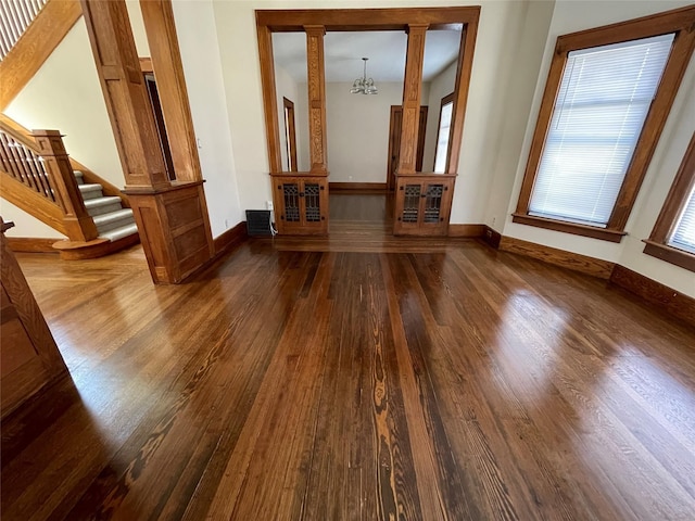 unfurnished living room with dark hardwood / wood-style flooring and a notable chandelier