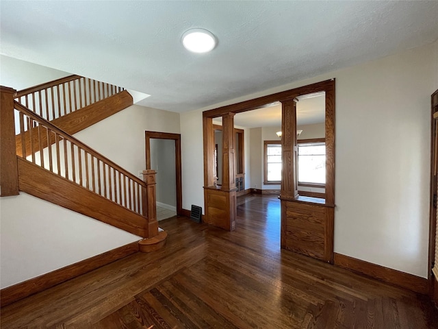 spare room featuring decorative columns and dark hardwood / wood-style floors