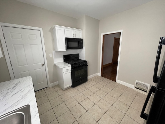 kitchen with light tile patterned flooring, black appliances, and white cabinets