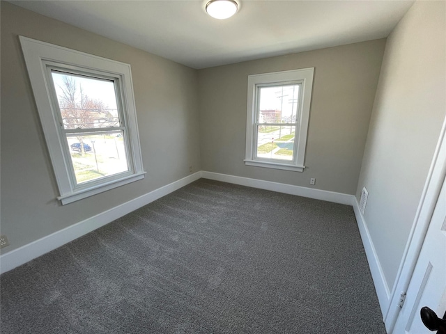 empty room with dark colored carpet and a healthy amount of sunlight