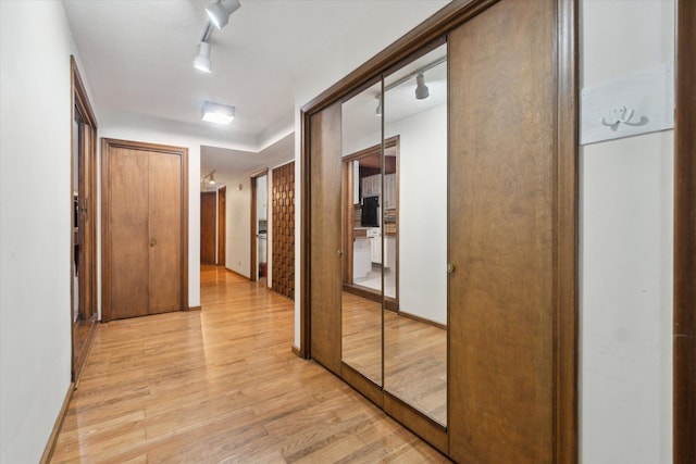 corridor with light hardwood / wood-style flooring and track lighting