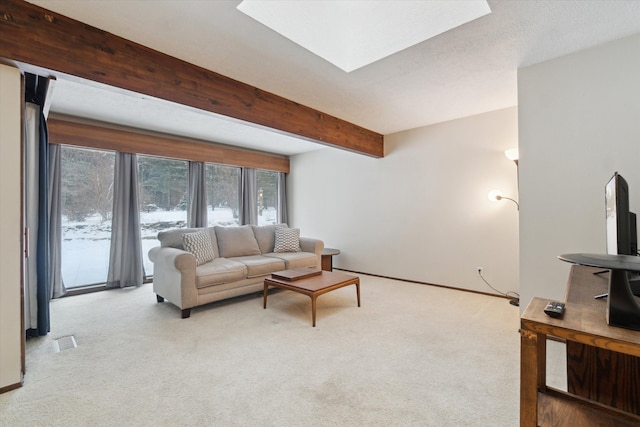 carpeted living room with a skylight and beam ceiling