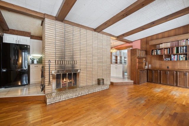 living room featuring wood walls, light hardwood / wood-style flooring, a fireplace, and lofted ceiling with beams