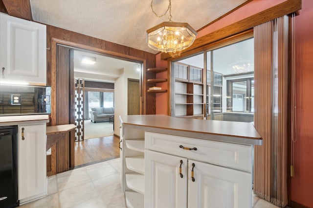 kitchen with decorative light fixtures, white cabinets, black dishwasher, and an inviting chandelier