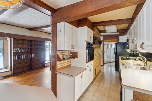 kitchen featuring plenty of natural light, white cabinetry, wall oven, and beam ceiling