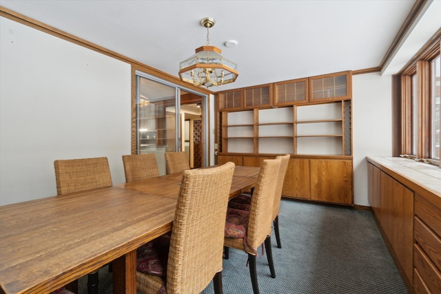 carpeted dining area with a notable chandelier and crown molding