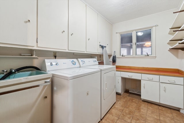 laundry area featuring a textured ceiling, washing machine and clothes dryer, light tile patterned floors, sink, and cabinets