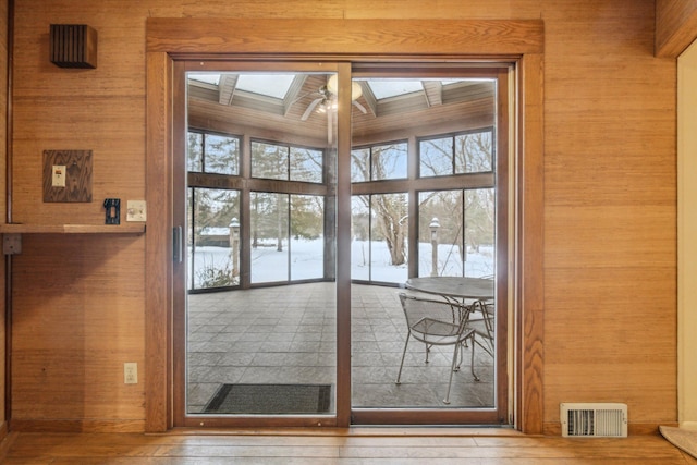 doorway featuring a skylight and wooden walls