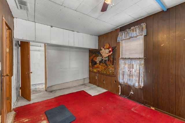 interior space with ceiling fan and wood walls