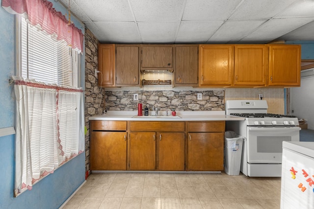 kitchen with white range with gas stovetop, a paneled ceiling, tasteful backsplash, and sink