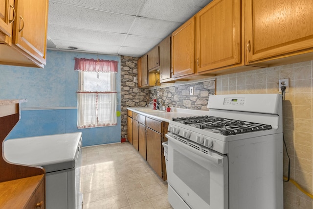 kitchen with sink, a paneled ceiling, and gas range gas stove