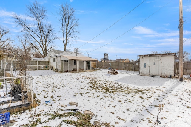 snow covered rear of property featuring a storage shed