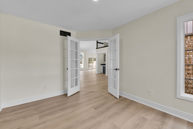 spare room featuring light wood-type flooring and french doors