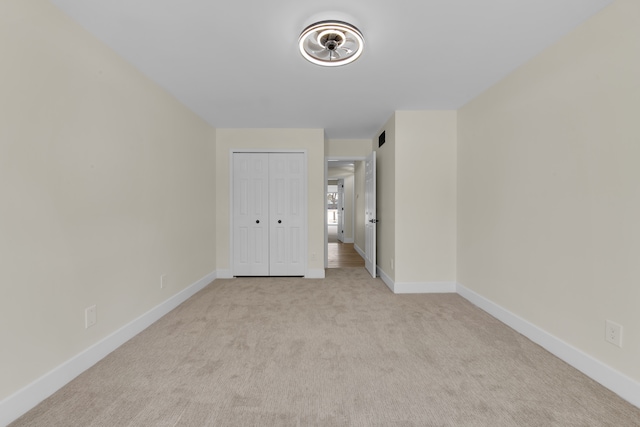 unfurnished bedroom with light colored carpet and a closet