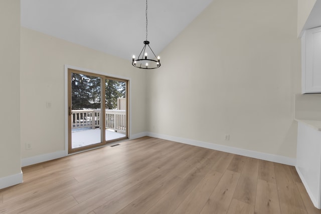 unfurnished dining area with light wood-type flooring, a chandelier, and high vaulted ceiling