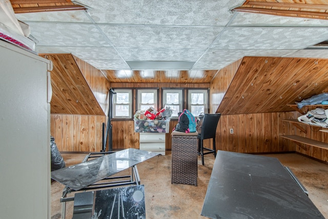 bonus room with concrete floors and wood walls