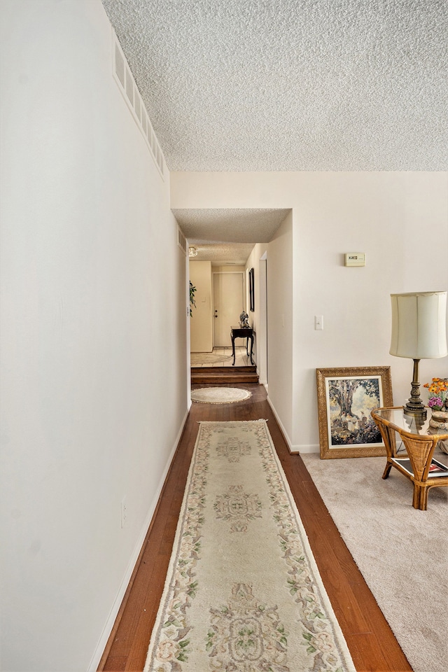 corridor with hardwood / wood-style floors and a textured ceiling