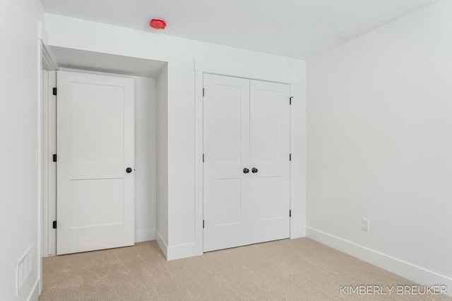 unfurnished bedroom with light carpet and a closet