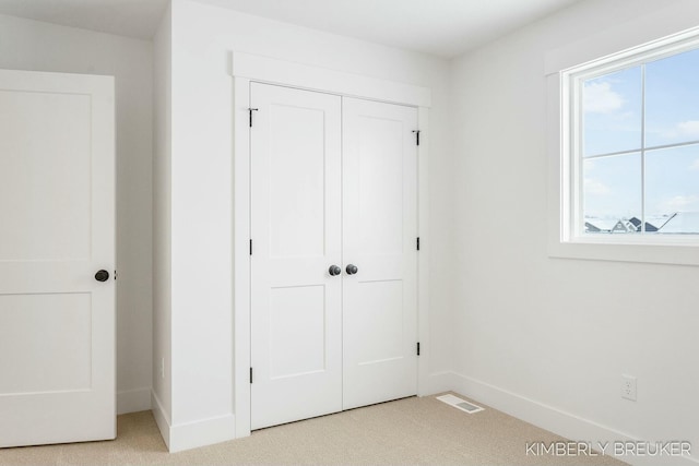 unfurnished bedroom featuring light carpet and a closet