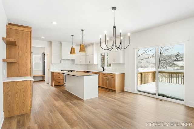 kitchen with a center island, decorative light fixtures, white cabinetry, a chandelier, and light hardwood / wood-style flooring