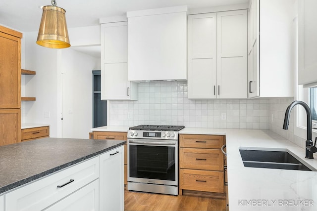 kitchen featuring gas range, sink, decorative light fixtures, white cabinetry, and decorative backsplash