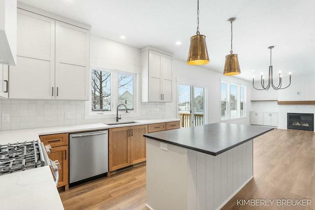 kitchen with sink, hanging light fixtures, white cabinets, and stainless steel appliances