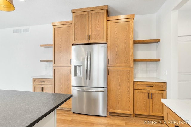 kitchen featuring light hardwood / wood-style floors, stainless steel fridge, and tasteful backsplash