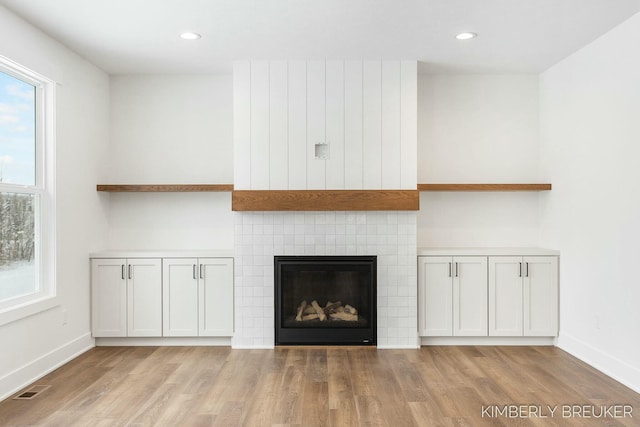 details with a tiled fireplace and wood-type flooring