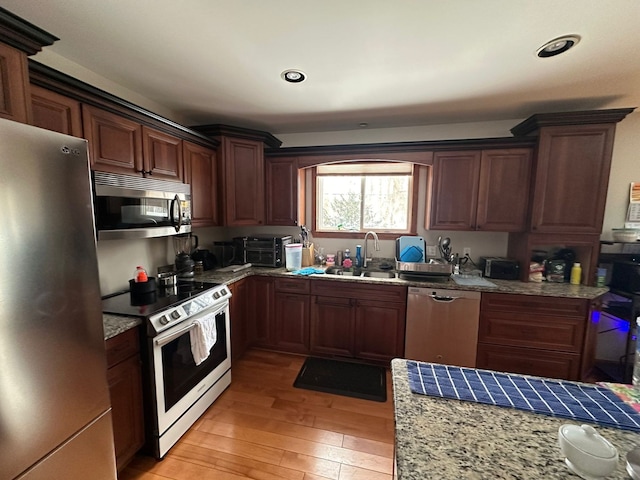 kitchen with sink, light hardwood / wood-style floors, light stone countertops, and appliances with stainless steel finishes