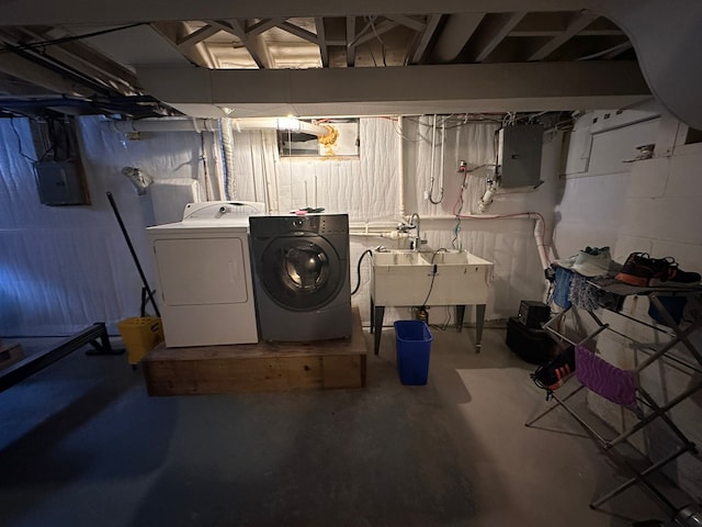 basement featuring washing machine and dryer, electric panel, and sink