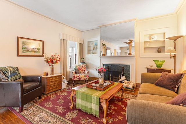 living room with built in shelves, ornamental molding, wood finished floors, and a premium fireplace