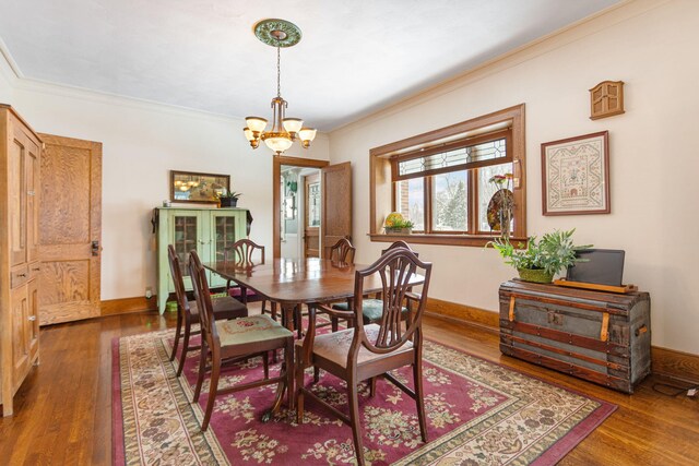 dining area featuring baseboards, ornamental molding, a chandelier, and wood finished floors