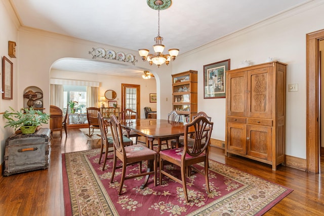 dining room with baseboards, arched walkways, ornamental molding, dark wood-style flooring, and an inviting chandelier