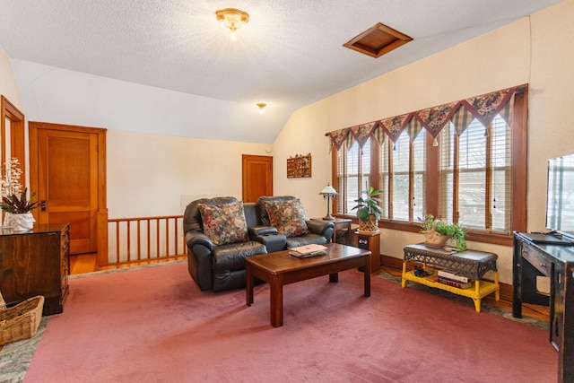 living area featuring lofted ceiling, attic access, carpet floors, and a textured ceiling