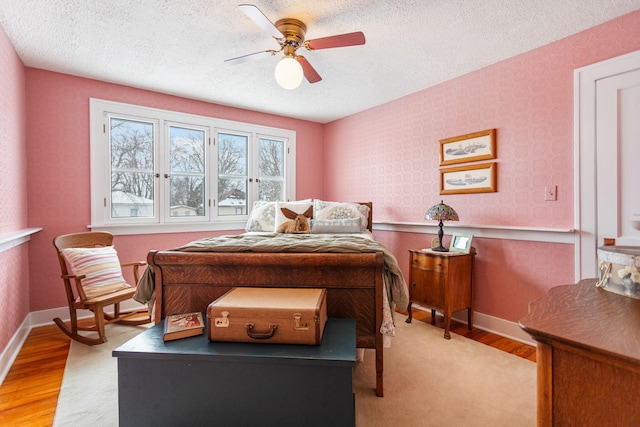 bedroom with a textured ceiling, light wood-style flooring, and wallpapered walls