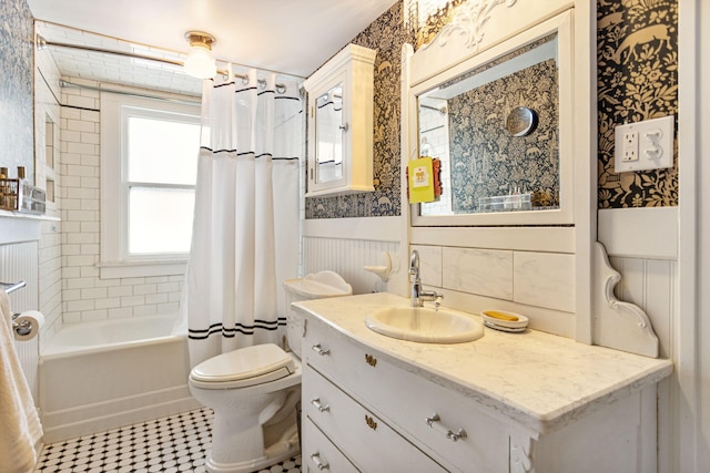 bathroom with toilet, wallpapered walls, shower / bath combo, and a wainscoted wall