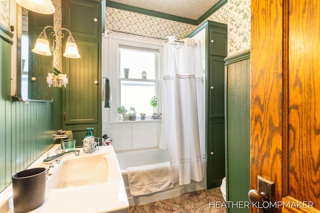 full bath featuring crown molding, shower / tub combo, a sink, and wallpapered walls