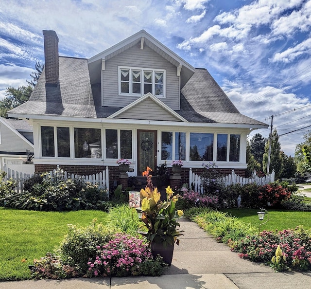 view of front of house with brick siding, a chimney, a front yard, and a shingled roof