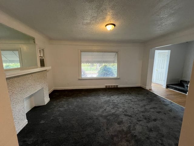 unfurnished living room with a textured ceiling and dark carpet