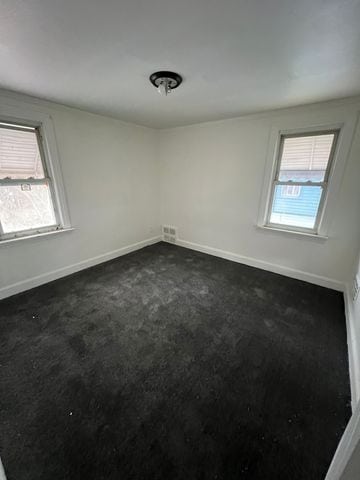 unfurnished room featuring dark colored carpet