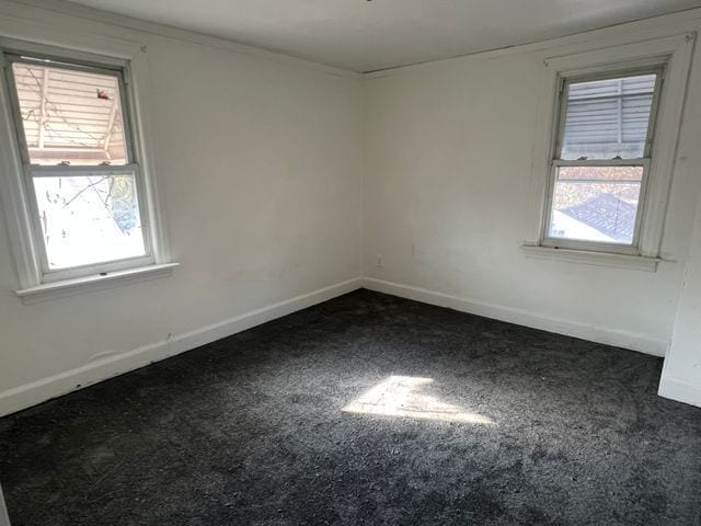 empty room with dark carpet and a healthy amount of sunlight