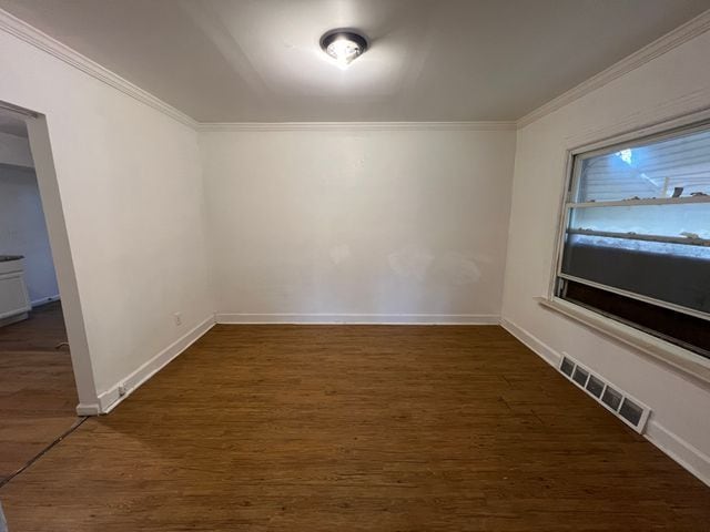 empty room with crown molding and dark hardwood / wood-style flooring