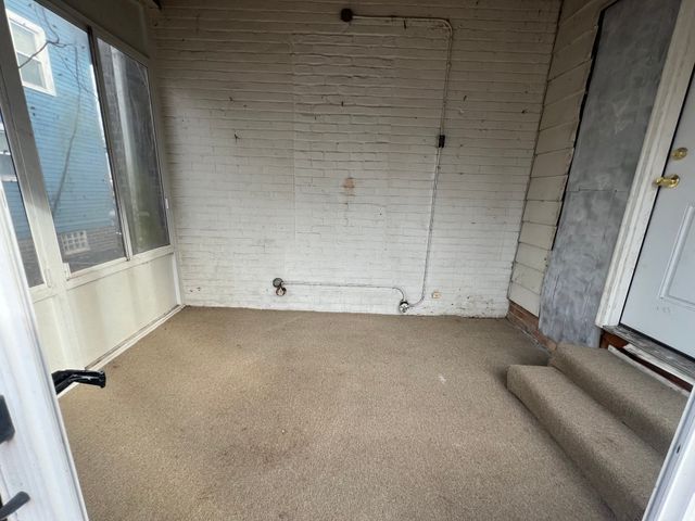 empty room with carpet floors and brick wall